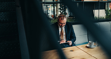Suited man sitting at table using a tablet