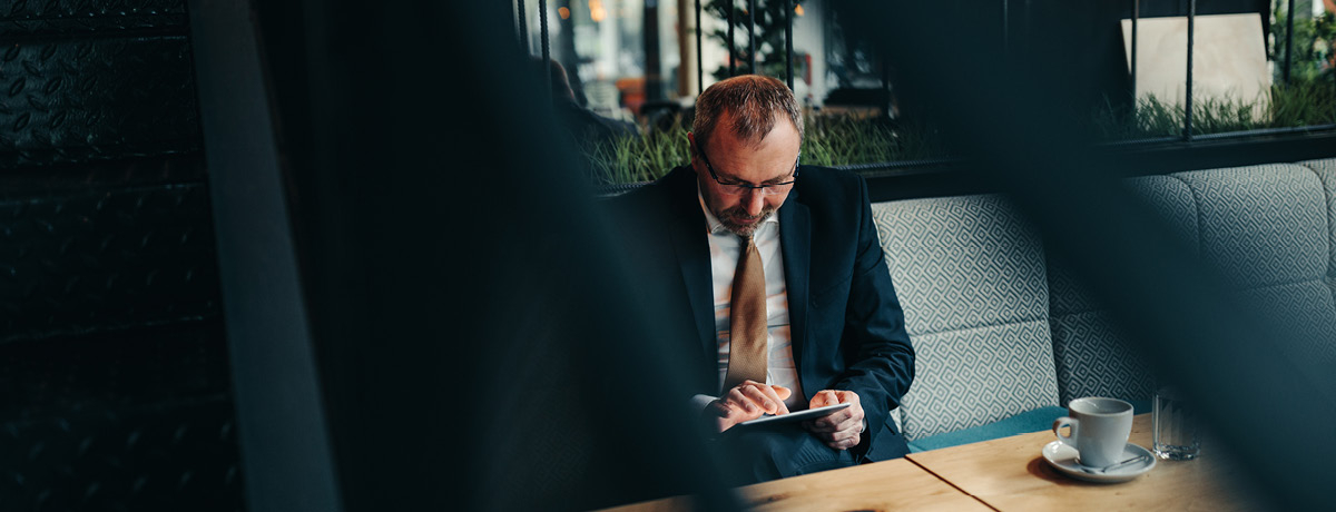 Suited man sitting at table using a tablet