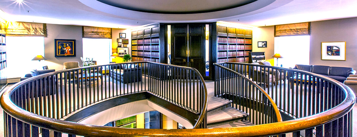 Top of a Staircase Featuring Two Large Black Doors with Bookshelves and Chairs on Each Side