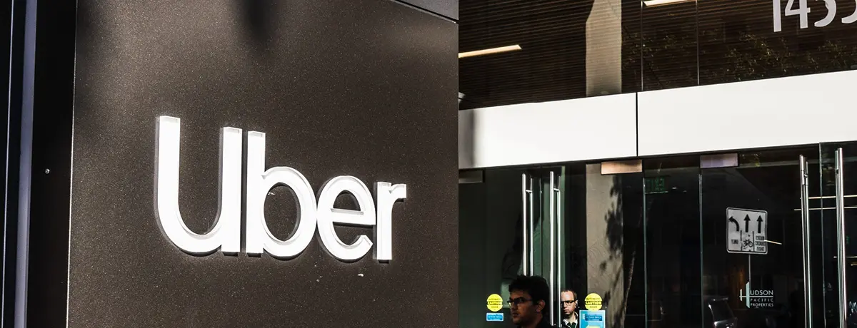 Exterior view of an Uber office building featuring the company's white logo on a dark wall.
