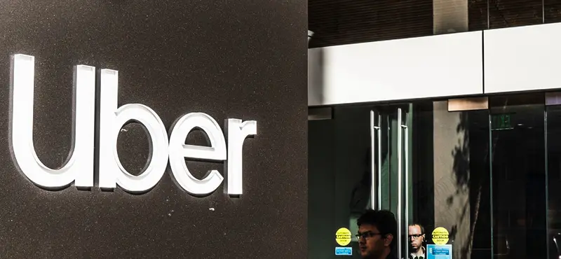Exterior view of an Uber office building featuring the company's white logo on a dark wall.