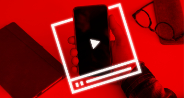 Man holding a phone inside of a box with a notebook and glasses on the table with a red filter