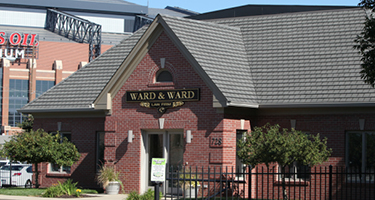 Law Firm building outside Lucas Oil stadium with green shrubs and blue background