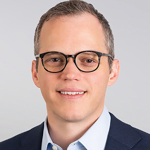 Lawyer wearing glasses and suit smiles in headshot photo