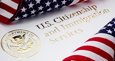 Two U.S. flags surround gold text and official seal