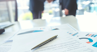 Close-up of legal documents on a desk with lawyers blurred in the background