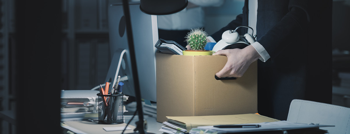 Close-up of person's hands holding a cardboard box filled with belongings after being terminated