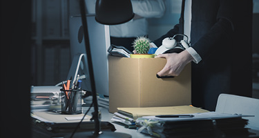Close-up of person's hands holding a cardboard box filled with belongings after being terminated