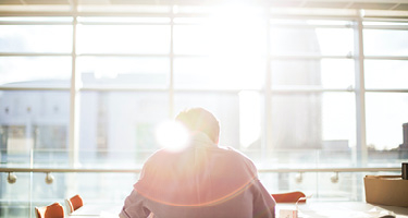 Bright sun shining through office window on man with head down