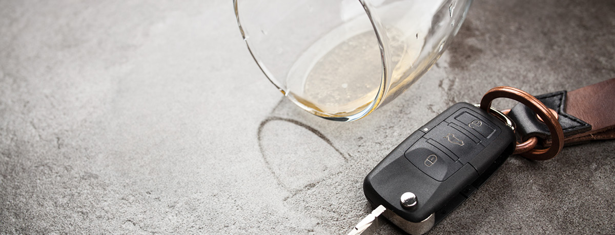 Car keys next to a spilled alcoholic drink, illustrating how a DUI arrest can lead to misdemeanor or
