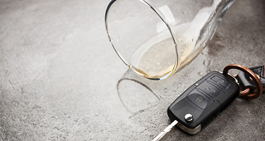 Car keys next to a spilled alcoholic drink, illustrating how a DUI arrest can lead to misdemeanor or