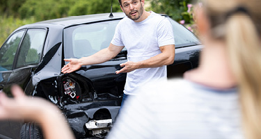 Man Examining Damaged Car