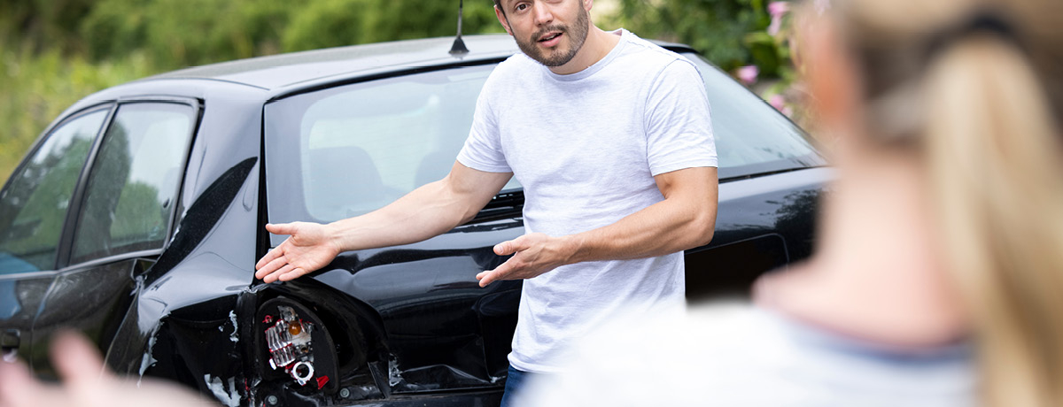 Man Examining Damaged Car