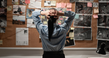 Woman with hands on head stares at board of images