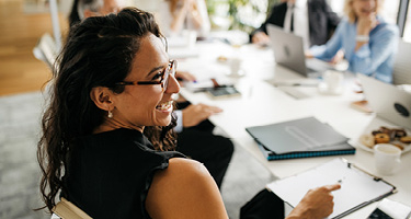 Woman sitting at boardroom table with several other people
