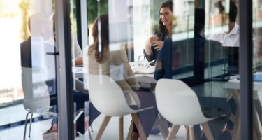 Boardroom of employees sit around a table discussing