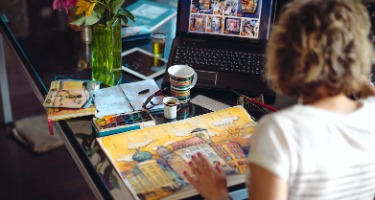 Woman sitting by a table with a map and a phone on a cluttered coffee table