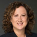 Headshot of female lawyer in dark suit with curly brown hair